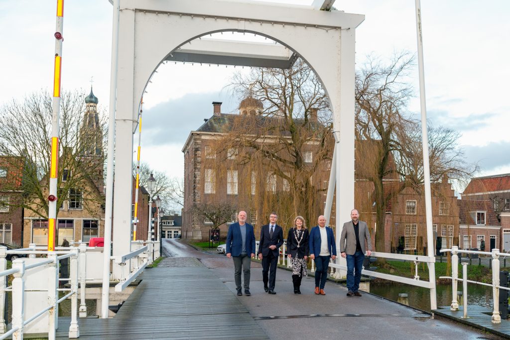 Het college van B en W van Enkhuizen loopt samen over de Compagniesbrug met op de achtergrond het raadhuis. Met van links naar rechts wethouder Wim Hoogervorst, wethouder Win Bijman, burgemeester Jeltje Hoekstra-Sikkema, wethouder Jan Franx en gemeentesecretaris Rob van Reijswoud.